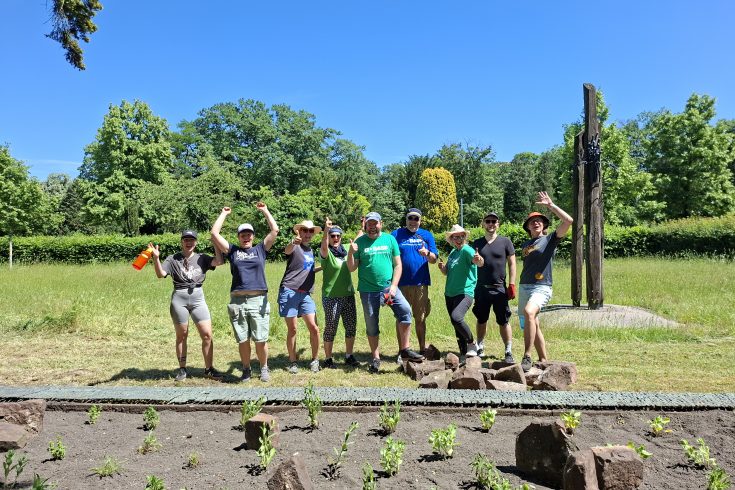 Freudiges Gruppenbild der TeilnehmerInnen nach der Anlage eines neuen Staudenbeets auf der Kriegsgräberanlage auf dem Hauptfriedhof Mannheim